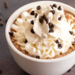 chocolate chips hot chocolate in mug topped with whipped cream and mini chocolate chips