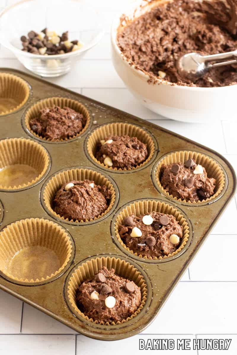 batter in bowl with scoop and muffin tin with paper cups and batter