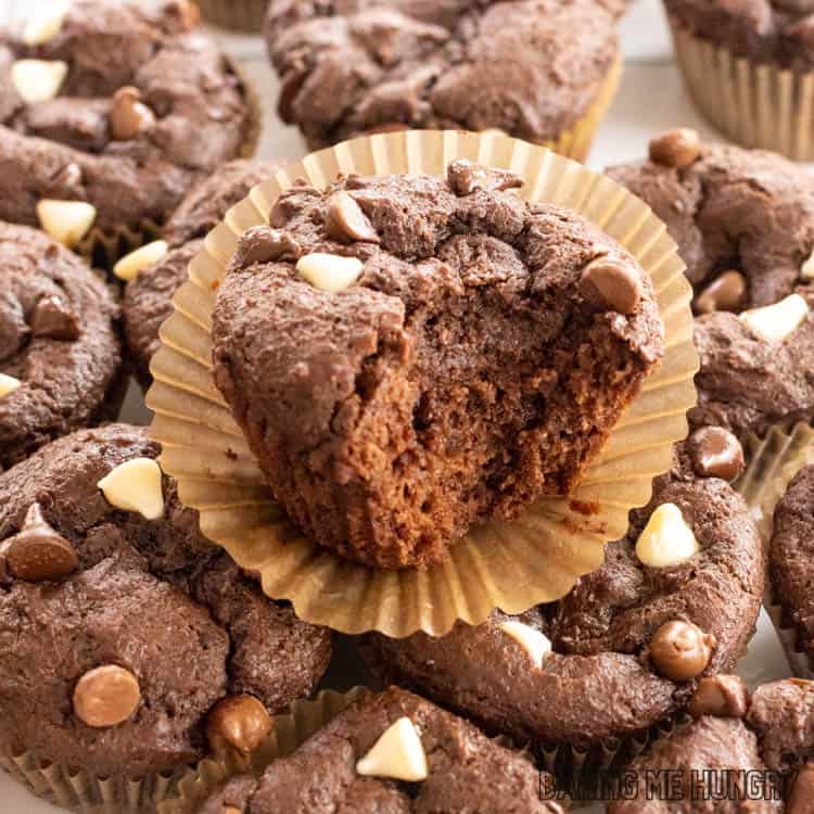 one of the triple chocolate muffins with a bite missing on top of more muffins