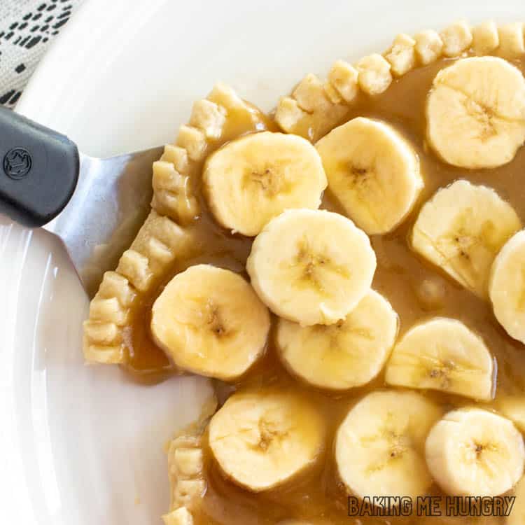 pie serving removing piece of banana tart with caramel