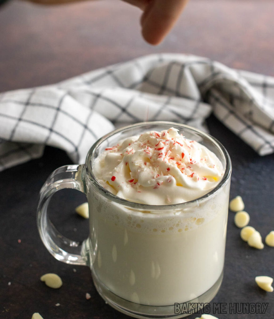 hand sprinkling crushed candy canes on top of whipped cream