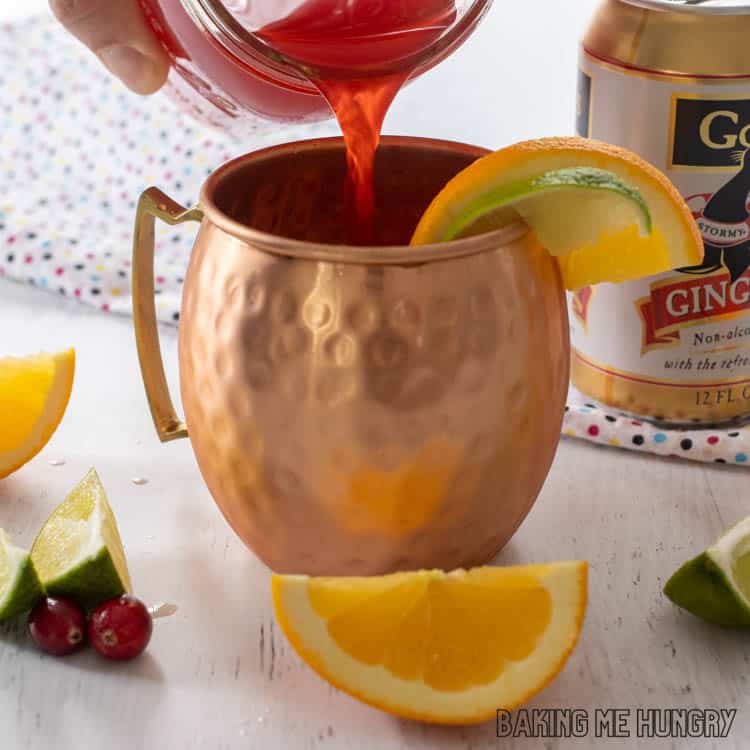 hand pouring cranberry juice into copper mug