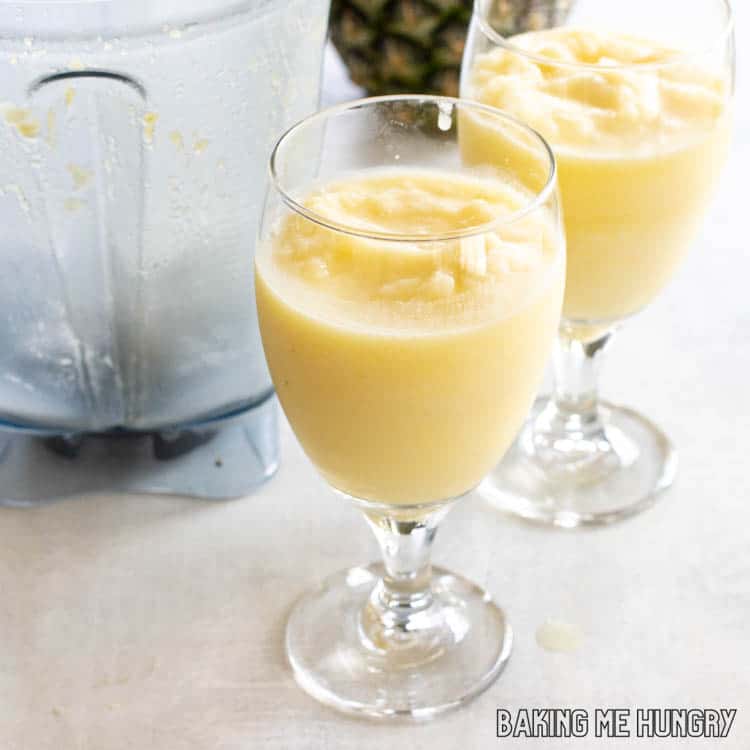 blender next to two glasses with pineapple coconut drink