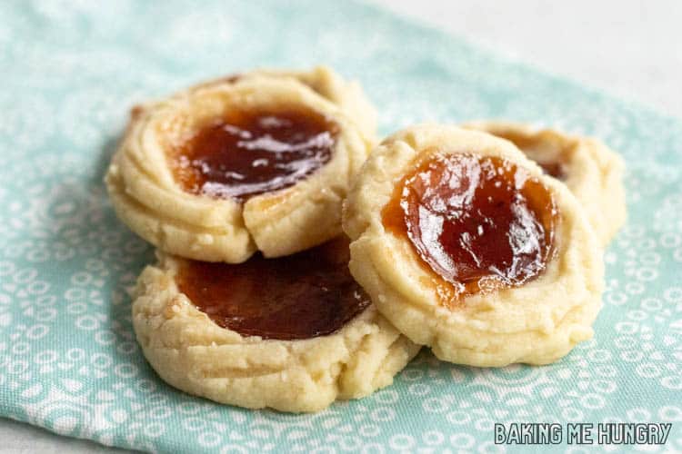 pile of shortbread cookies with strawberry jam sitting on light blue napkin