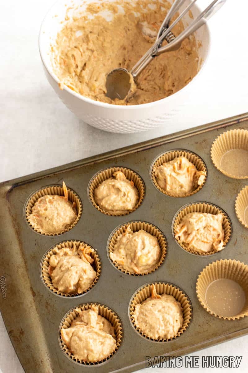 cookie scoop in batter and batter in cupcake pan with liners