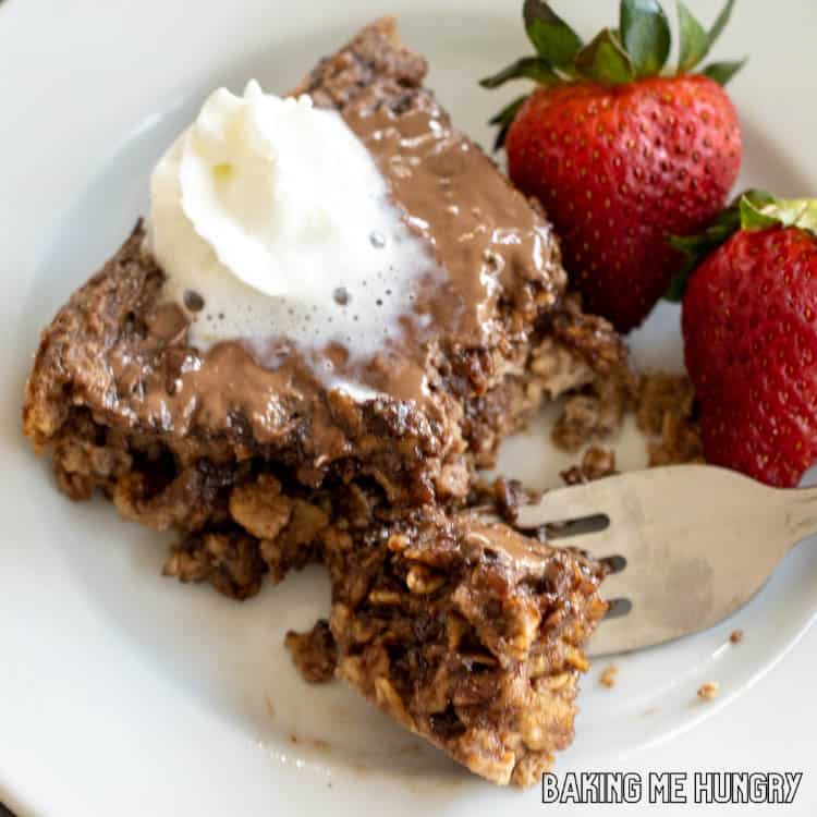 piece of nutella baked oats on plate with whipped cream and strawberries