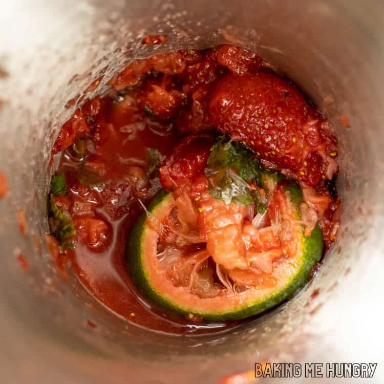 muddled strawberries, lime slices, and mint leaves in a cocktail shaker