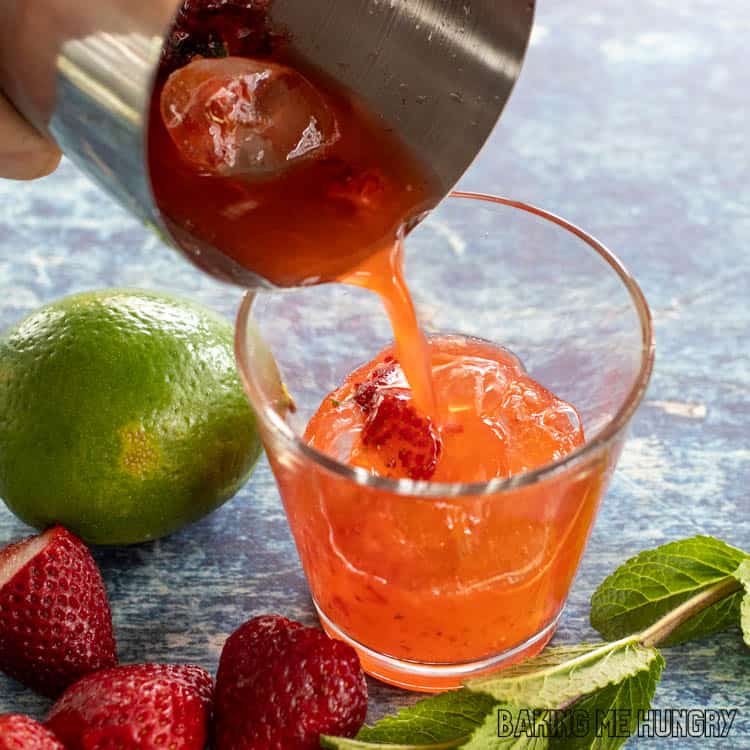 muddled berries, lime, and mint being poured into glass