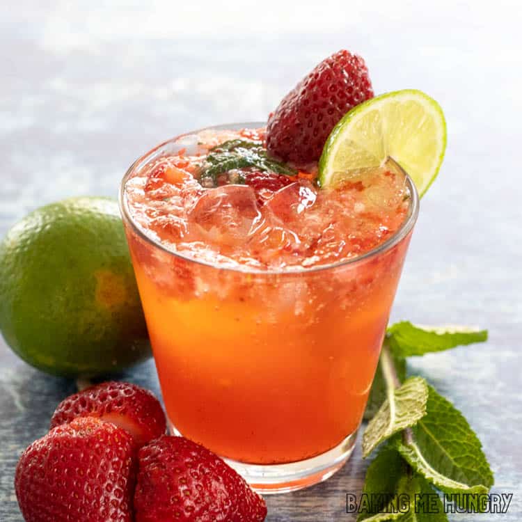 glass of virgin strawberry mojito garnished with a strawberry and lime slice