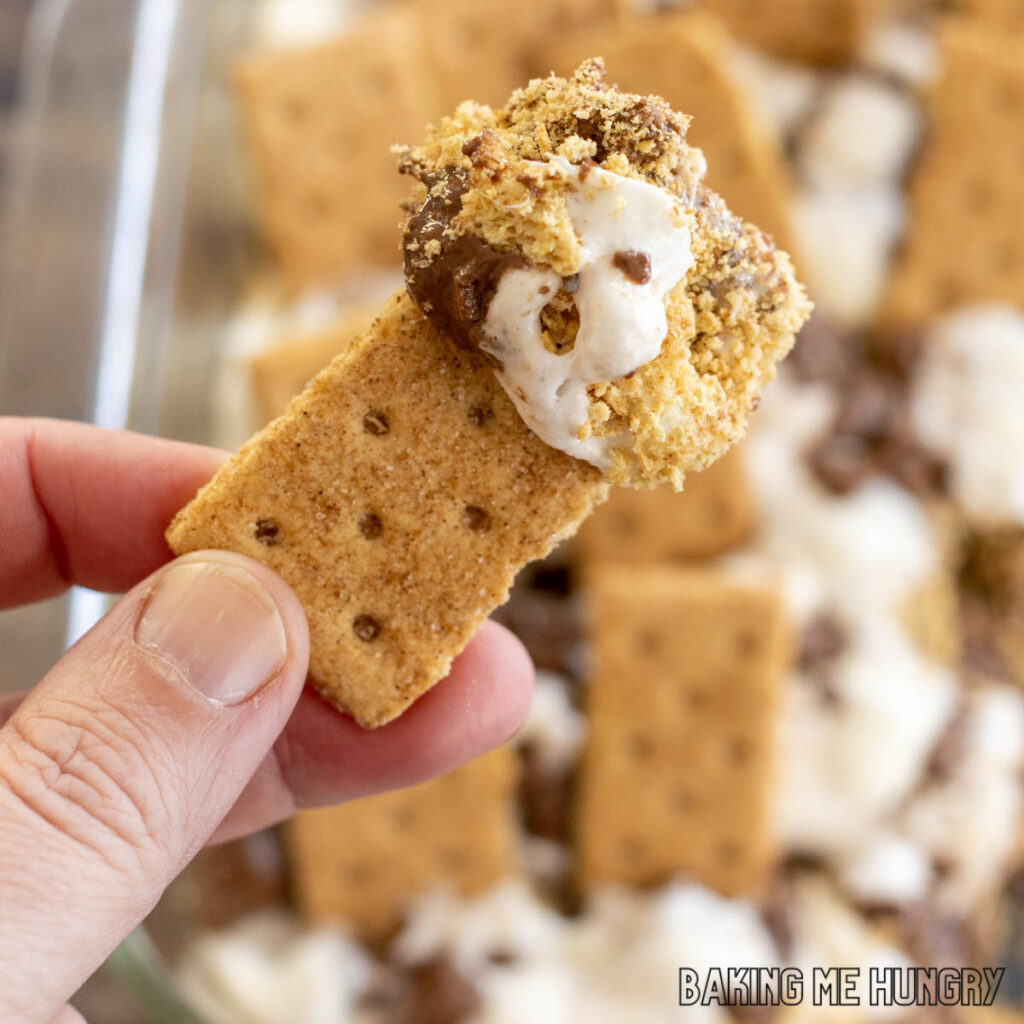 smores casserole recipe shown scooped onto a graham cracker