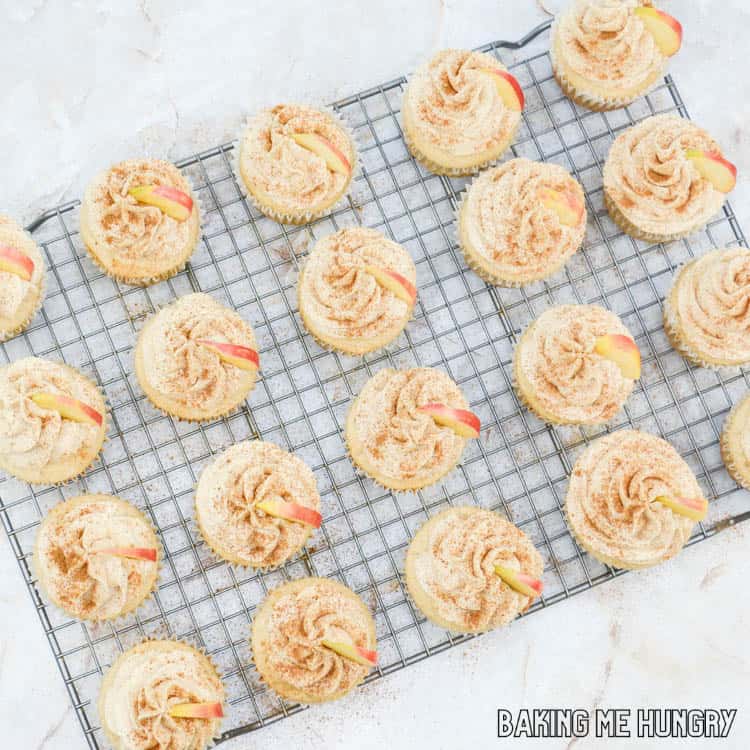 apple cider cupcakes garnished with cinnamon and apple slices on wire rack
