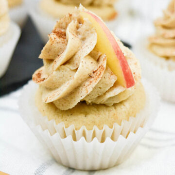 apple cider cupcakes with brown sugar cinnamon frosting sitting on paper liners