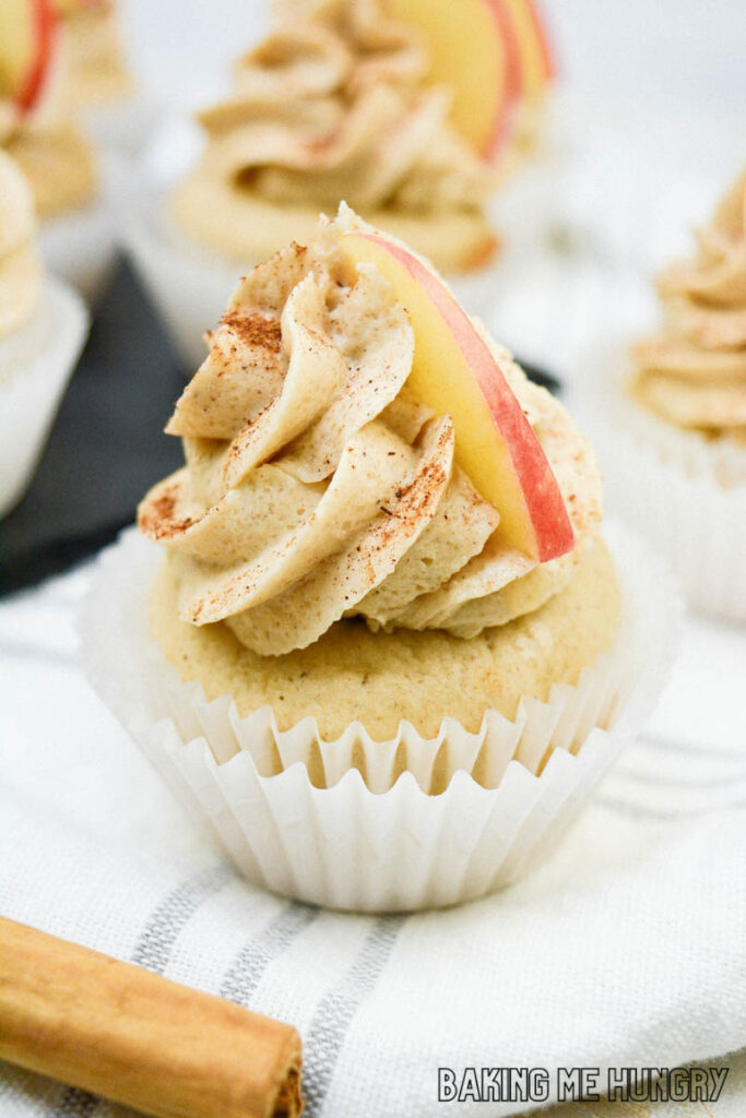 apple cider cupcakes with brown sugar cinnamon frosting sitting on paper liners
