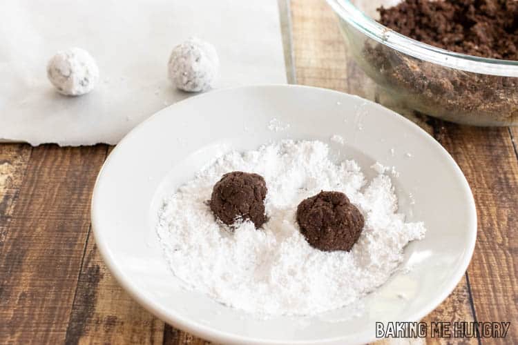 two balls of dough in bowl of powdered sugar