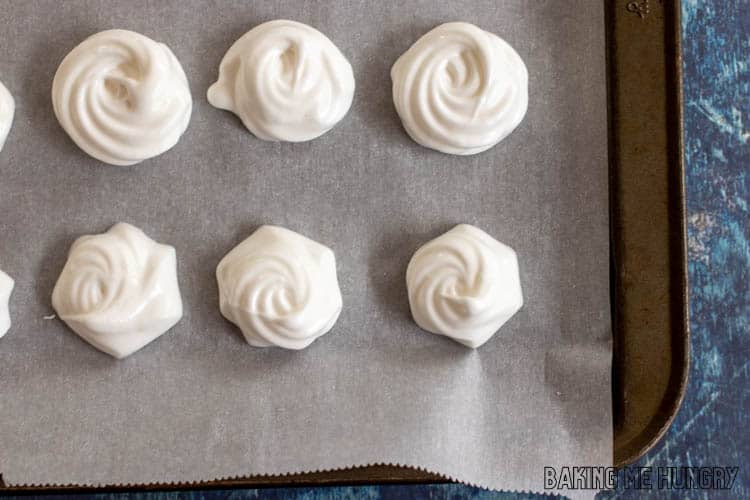 close up of baked mini meringues on parchment lined pan