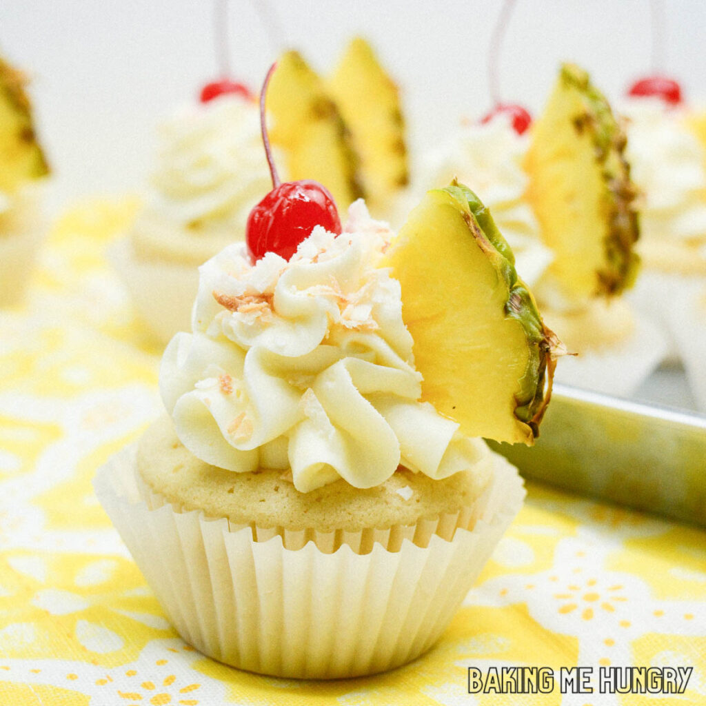 pineapple coconut cupcakes garnished with maraschino cherries on yellow cloth napkin