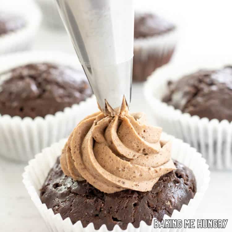 mocha frosting being piped onto cupcake
