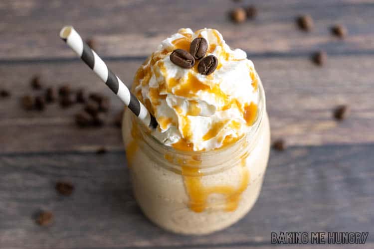 frosted coffee recipe in mason jar topped with whipped cream and coffee beans and drizzled with caramel