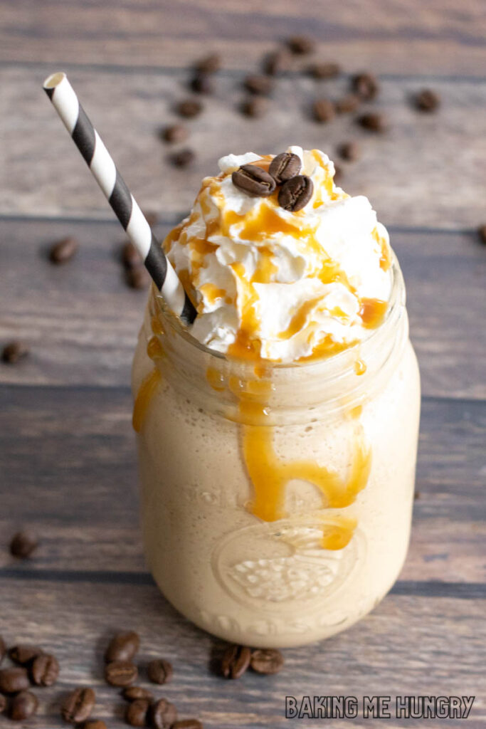 frosted coffee recipe in mason jar topped with whipped cream and coffee beans and drizzled with caramel