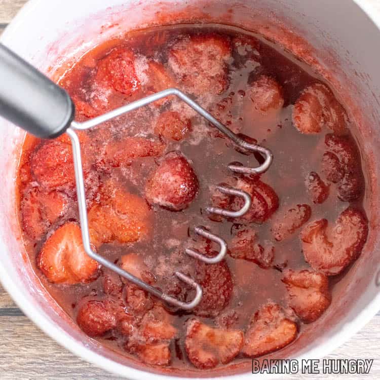 potato masher in saucepan of berries