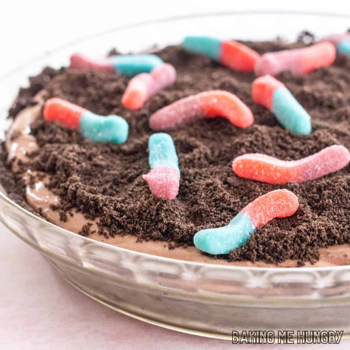 mud pie recipe with gummy worms shown from the side close up in glass pie plate