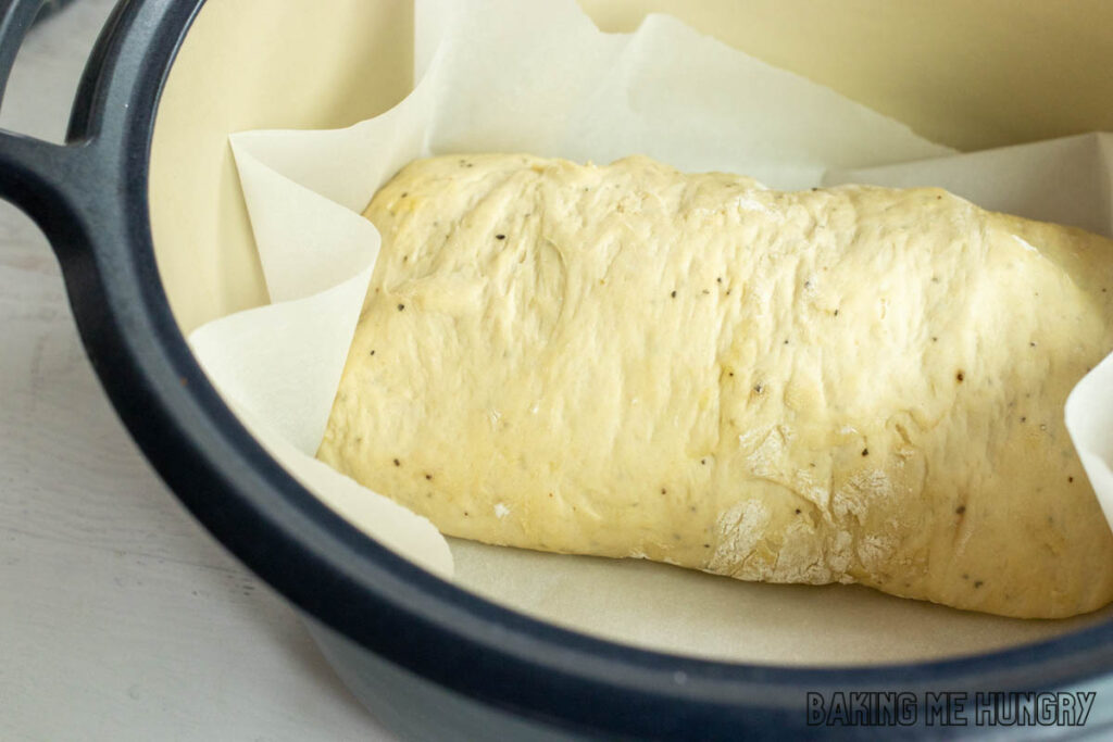 dough on parchment in cast iron pot