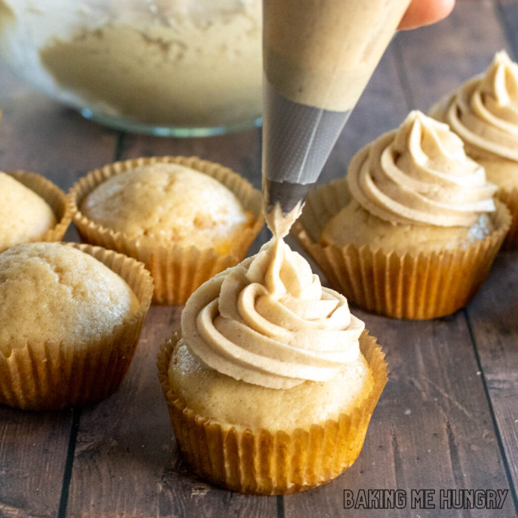 brown sugar cinnamon frosting being piped onto a cupcake