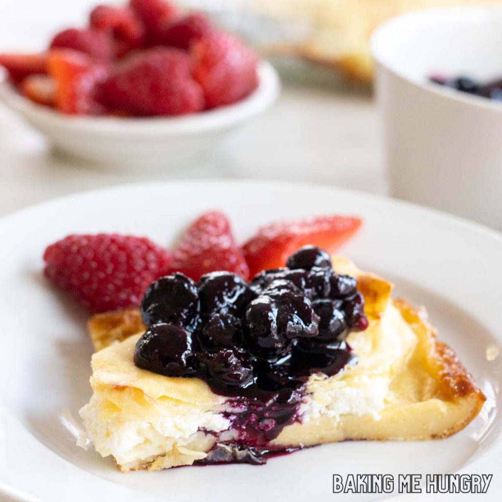 piece of cheese blintz casserole on a plate with blueberry sauce