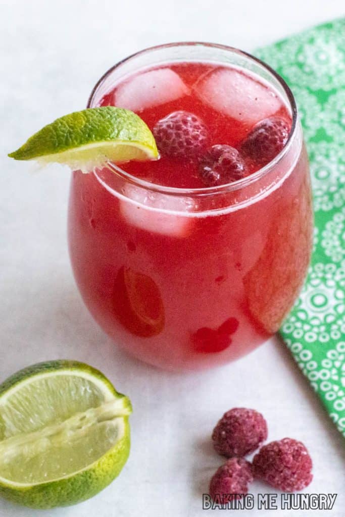 raspberry mocktail in wine glass with floating berries and lime slice