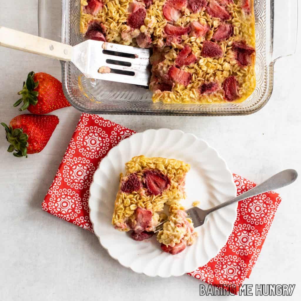 baking dish of strawberry baked oatmeal with serving on small plate