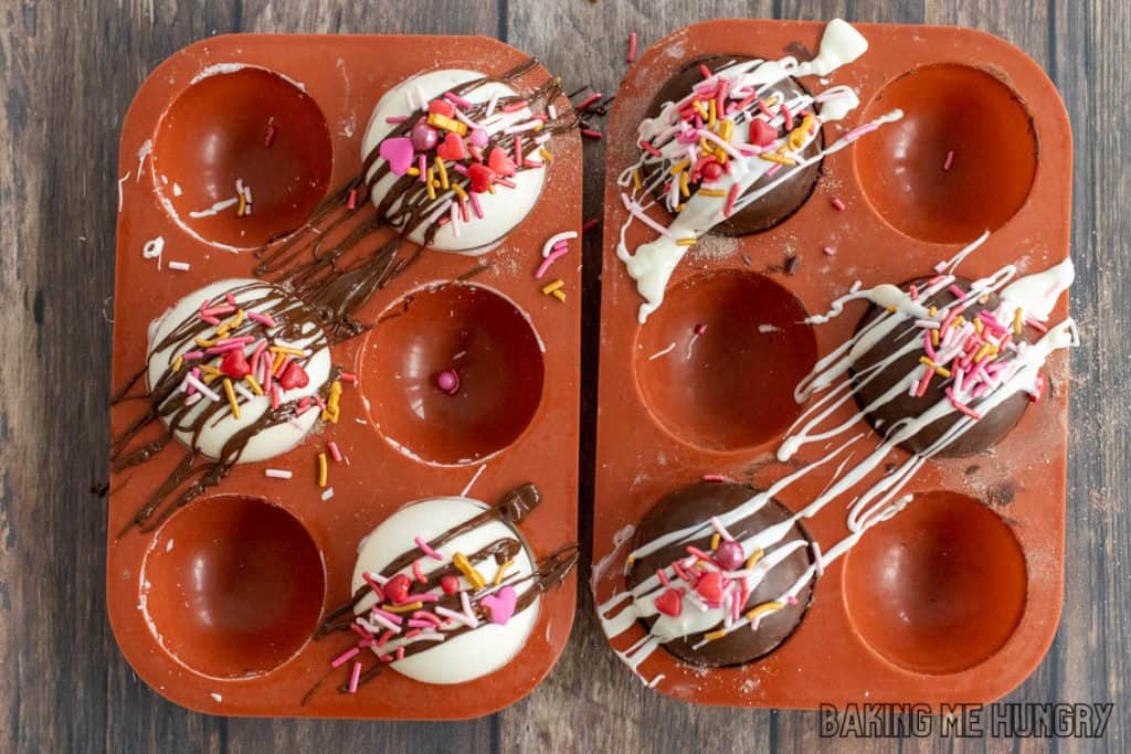 sprinkles added and chocolate drizzled over the completed hot cocoa bombs in mold