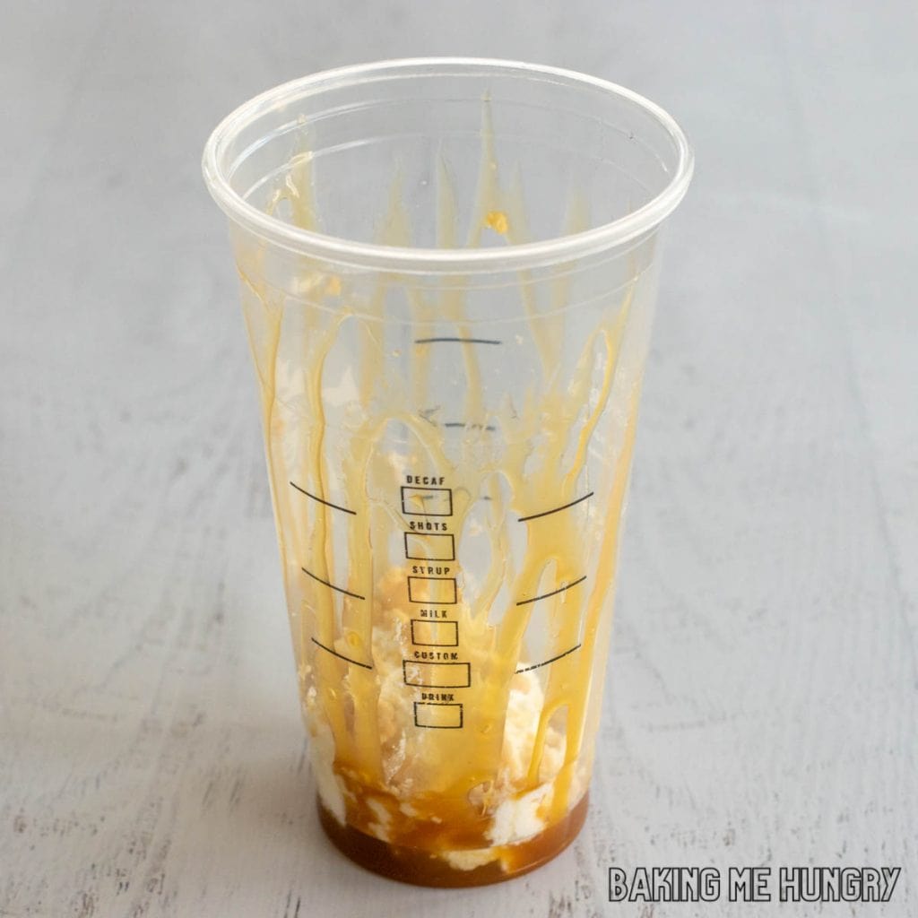 whipped cream and caramel sauce in the bottom of a large starbucks cup