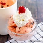 cherry cordial ice cream recipe served in a pedestal bowl topped with whipped cream and a maraschino cherry
