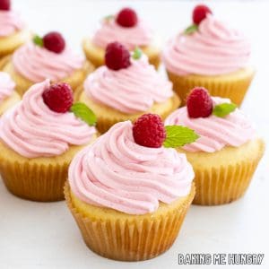 cupcakes topped with fresh raspberries and mint leaves