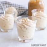 caramel mousse in small glasses with a jar of dulce de leche caramel sauce behind