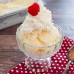 ice cream recipe without cream served in a pedestal dish with whipped cream and a cherry