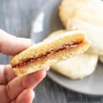 one of the raspberry and white chocolate cookies halved being held by a hand