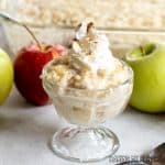 rice pudding with apples topped with whipped cream and cinnamon in small glass dish
