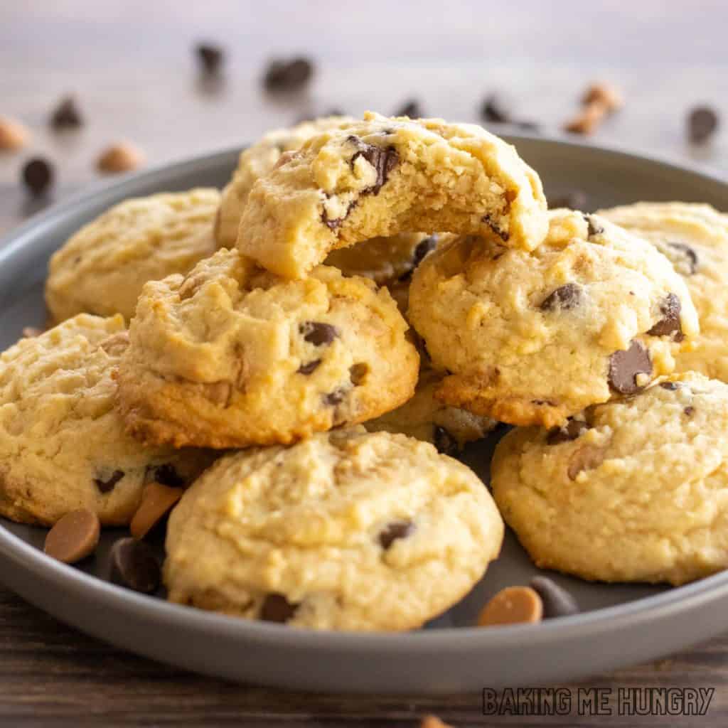 chocolate chip butterscotch cookies recipe piled on a serving plate with top cookie missing a bite