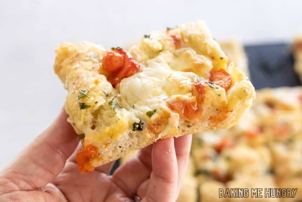 hand holding a piece of caprese focaccia