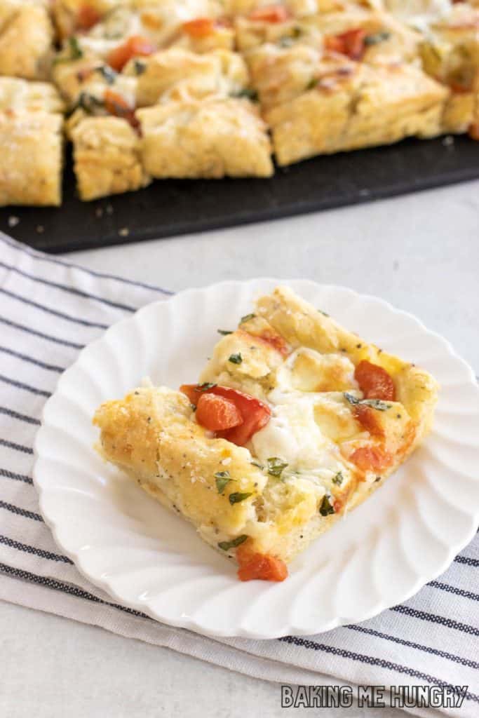 caprese focaccia piece on small plate with the rest behind