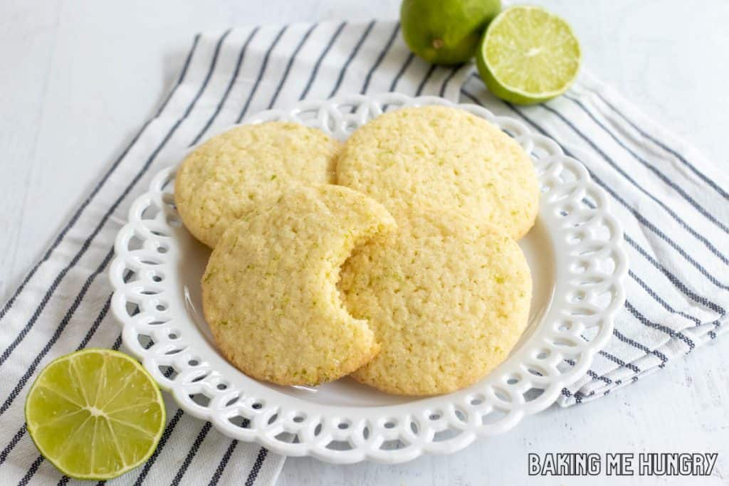 lime sugar cookies on a plate on a striped napkin with one missing a bite