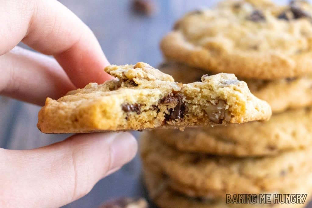 hand holding one of the chocolate chip pecan cookies missing a bite