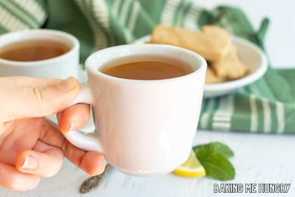 hand holding tea cup with honey citrus mint tea recipe