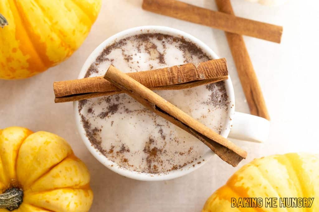 pumpkin chai latte recipe in a large mug with whipped cream and cinnamon sticks