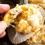 cheese and bacon muffins recipe shown as hand pulling muffin apart to show strings of cheese close up
