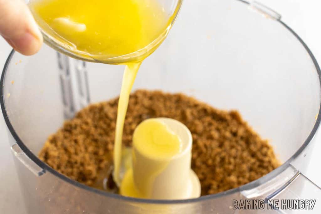 hand pouring melted butter into food processor