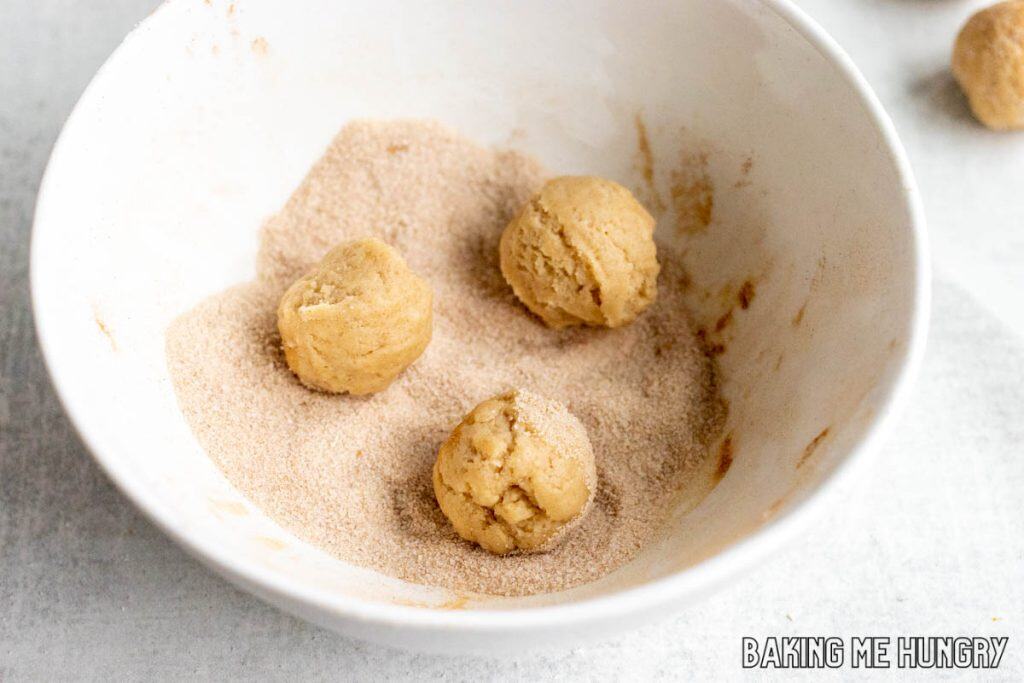 balls being rolled in cinnamon sugar in bowl