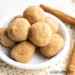 edible snickerdoodle dough balls in shallow dish with cinnamon sticks