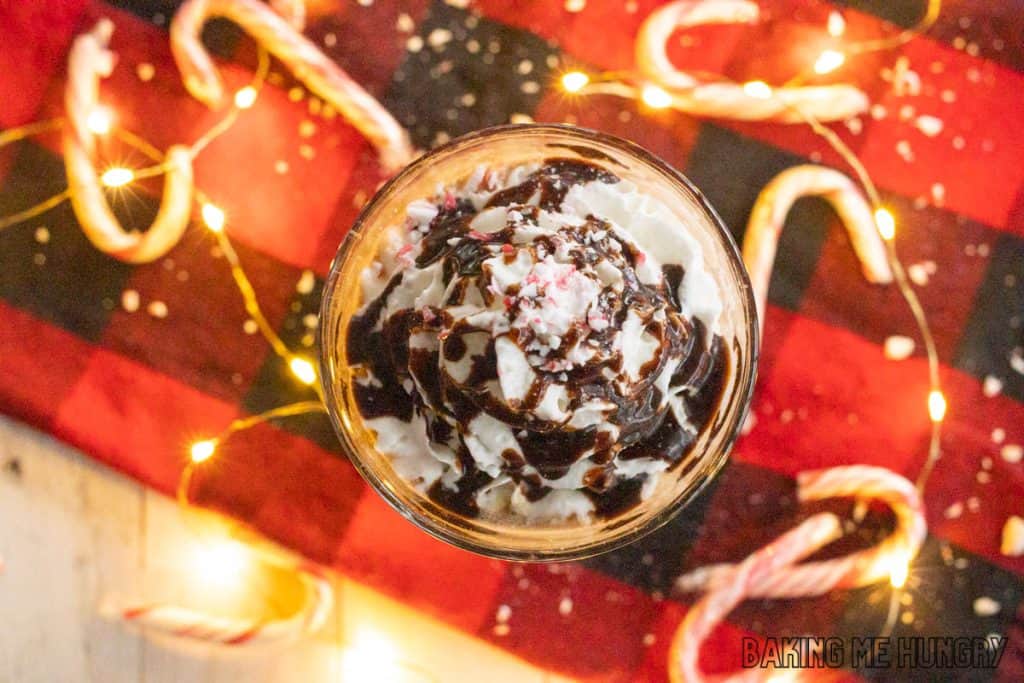overhead shot of iced peppermint mocha in a tall glass with fairy lights behind